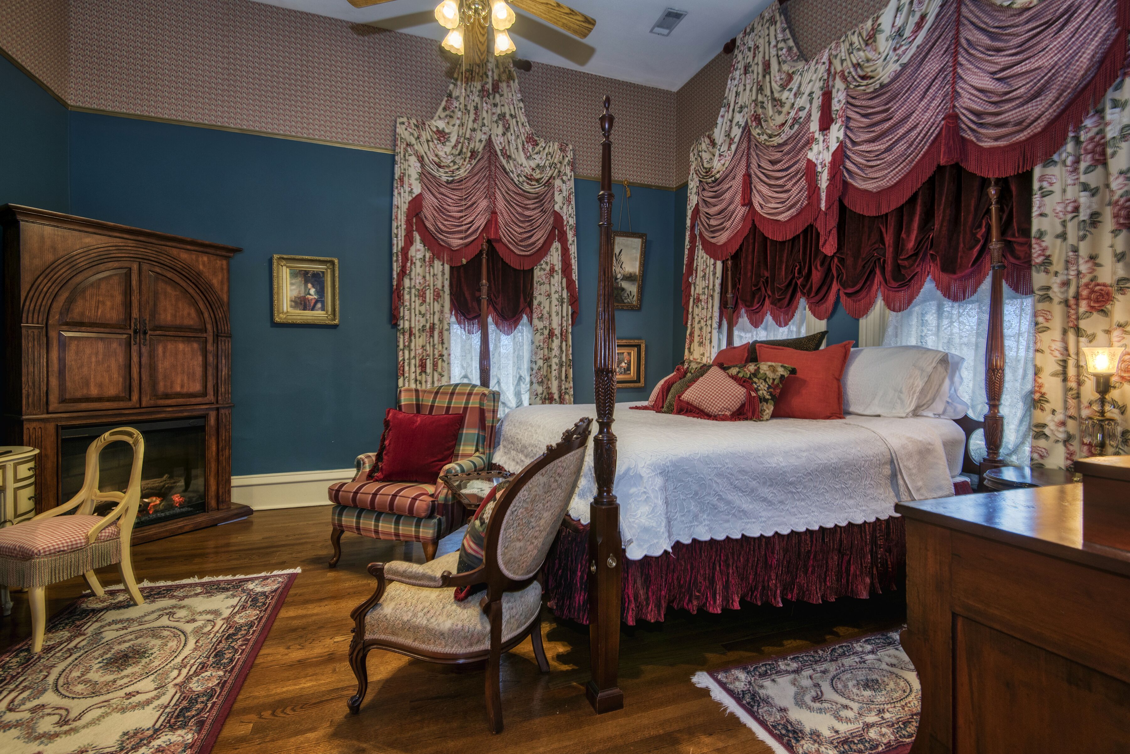 A traditional bedroom with a four-poster bed, a fireplace, and classic furniture.