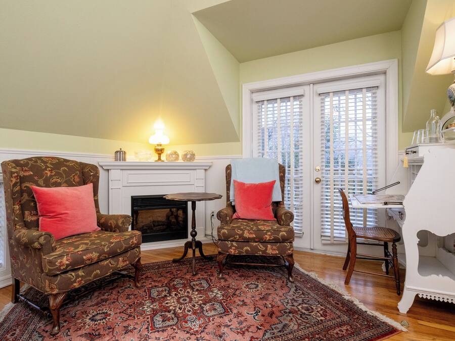 A living room with two armchairs, a fireplace, a dining table, and a white cabinet.
