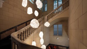 A grand staircase with a balustrade, a large window, and hanging light fixtures. - Chic&Basic Born Boutique Hotel (Barcelona)
