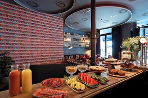 A breakfast buffet with various food items and beverages, a patterned wall, and a modern ceiling design. - chic&basic Born Boutique Hotel (Barcelona)