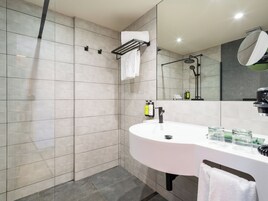 Un bagno moderno con uno specchio grande, un lavandino e una zona doccia.