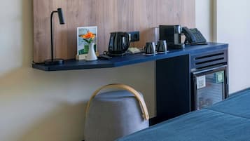 A modern room with a built-in shelf holding a lamp, a flower vase, a coffee maker, and a phone.