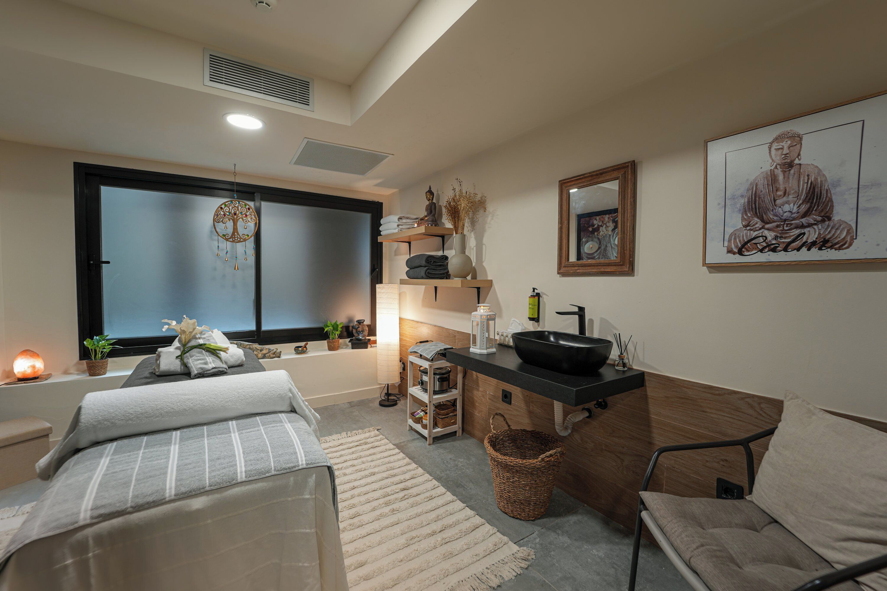 Un dormitorio moderno con cama, rincón de descanso, kitchenette pequeña y ventana grande.