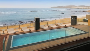 Una piscina en la azotea con vistas al océano y la playa.