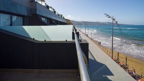Un edificio moderno con fachada de vidrio que da a una playa.