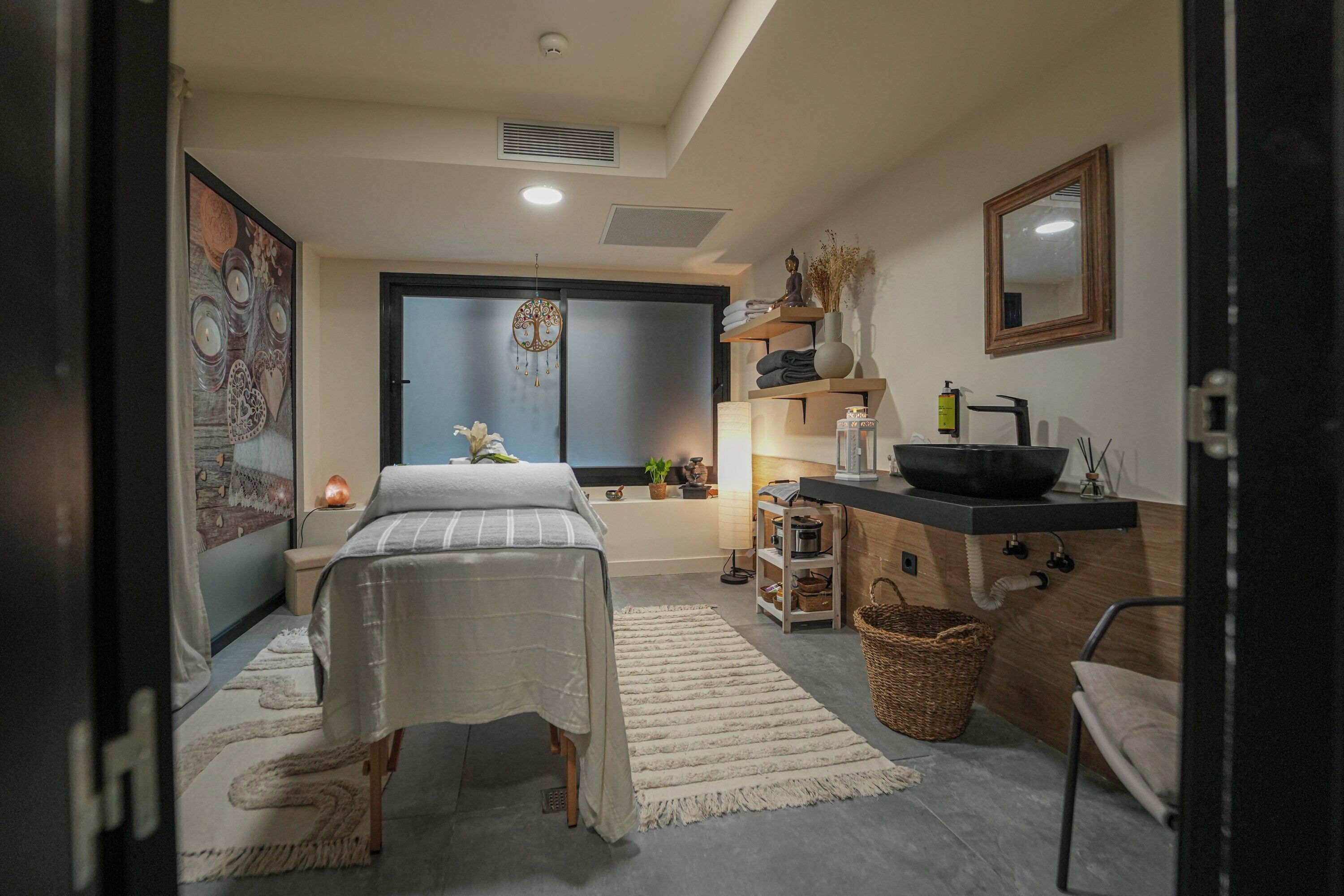 Una camera da letto con un letto, comodino, cassettiera, specchiera e una finestra con vista.