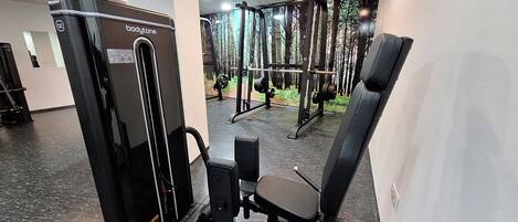 A gym with various exercise machines, including a bodytone machine, and a weight rack in the background.