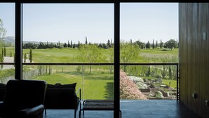 A room with large windows overlooking a landscaped area with trees and a golf course. - Hotel Terraverda at Empordà Golf Resort (Gualta)