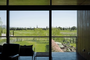 A room with large windows overlooking a landscaped area with trees and a golf course. - Hotel Terraverda at Empordà Golf Resort (Gualta)