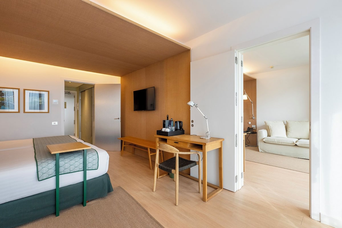 A modern hotel room with a bed, desk, chair, and a television.