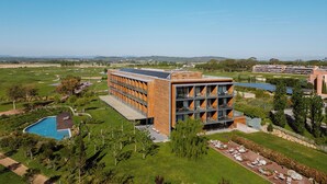 Un edificio moderno con piscina, rodeado de vegetación y un campo de golf.