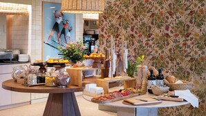 Una barra de buffet con diferentes alimentos, un papel tapiz floral y una lámpara de mimbre.