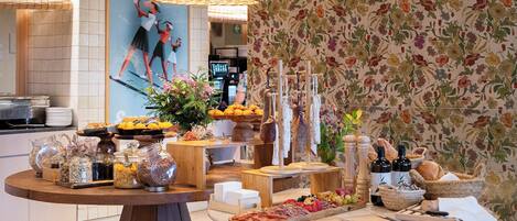 Una barra de buffet con diferentes alimentos, un papel tapiz floral y una lámpara de mimbre.