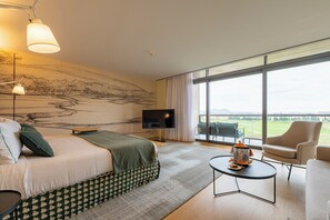 Hotelkamer met een bed, een televisie, een eettafel met stoel en een groot raam met uitzicht.