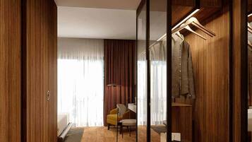 Una habitación de hotel moderna con un armario de madera, un escritorio, una silla y un perchero.