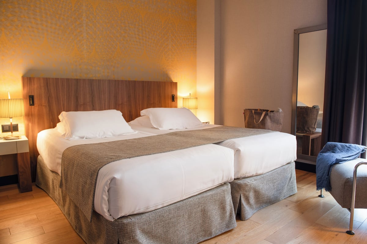 Une chambre d’hôtel avec un grand lit, une table de chevet, une lampe et un miroir.