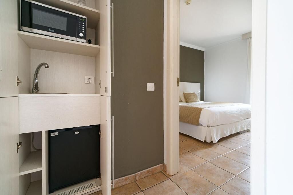 Een hotelkamer met een bed, een ingebouwde magnetron, een wastafel en een kleine koelkast.