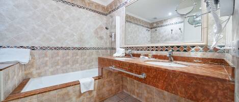 A bathroom with a bathtub, two sinks, a large mirror, and a hairdryer.