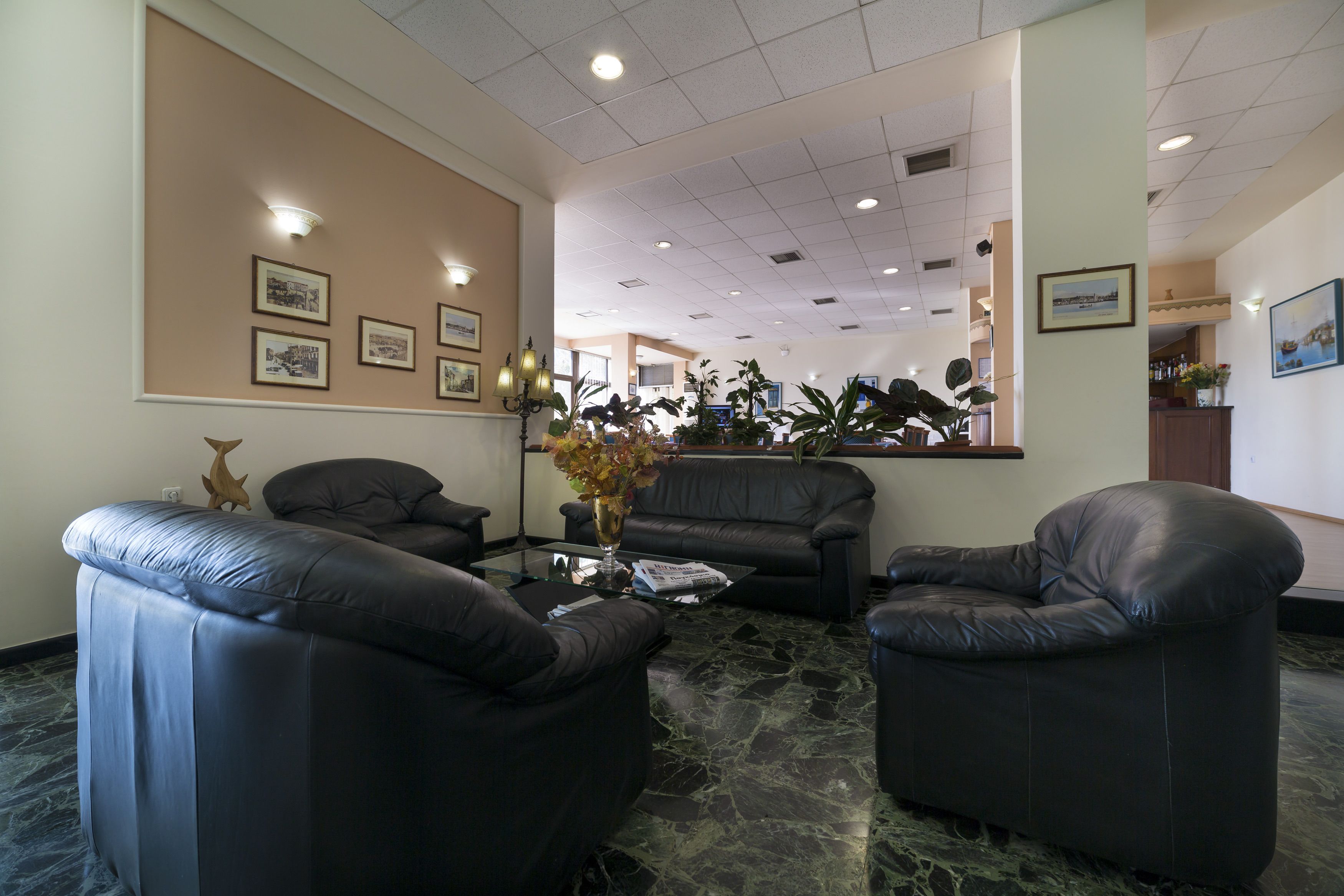 A lobby with leather sofas, a glass coffee table, and framed pictures on the walls.
