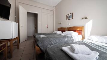 Habitación de hotel con dos camas, un televisor, un escritorio y una puerta que da a un pasillo.