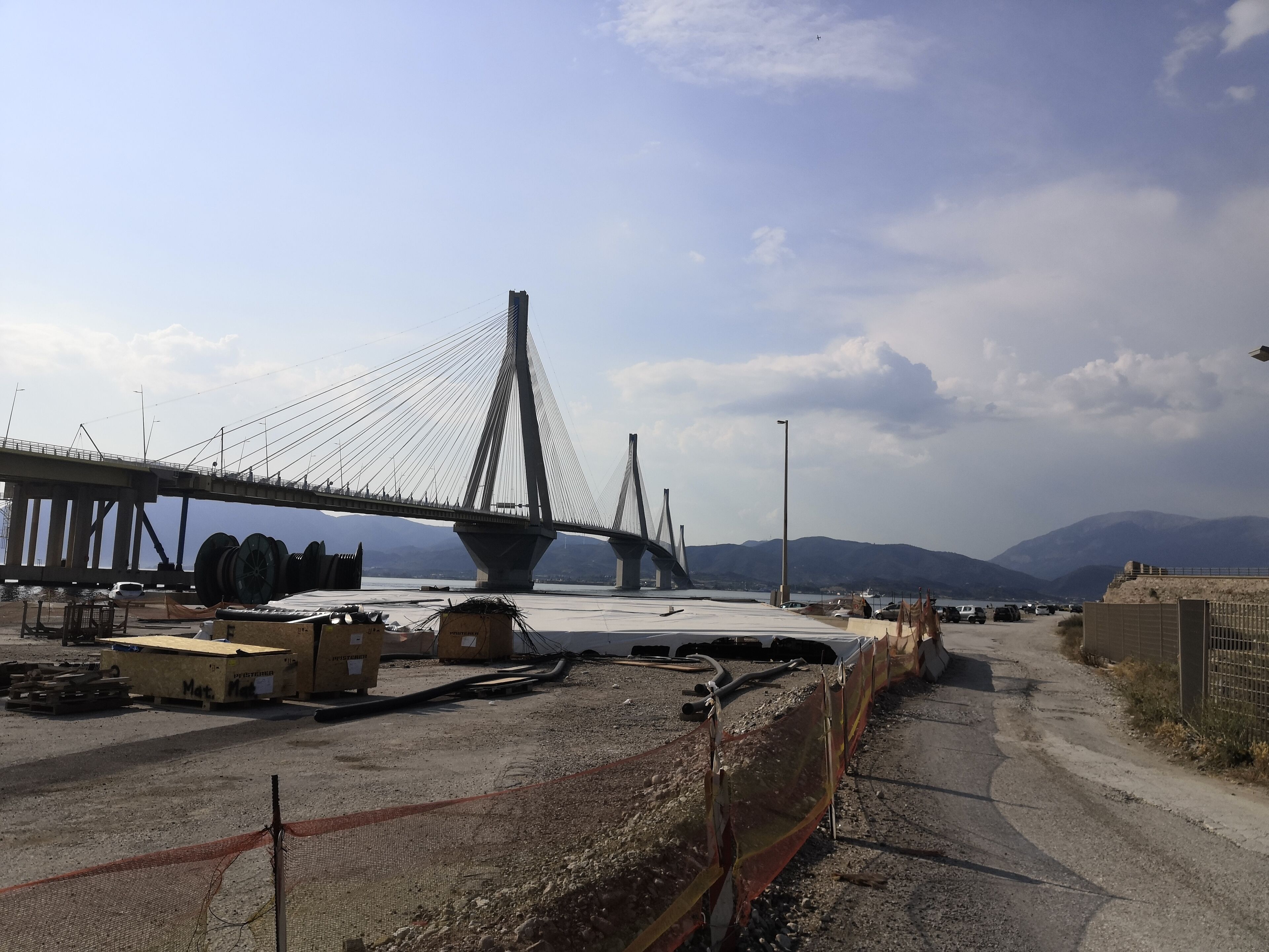 A construction site with a large bridge under construction, featuring multiple cables and a prominent central tower.