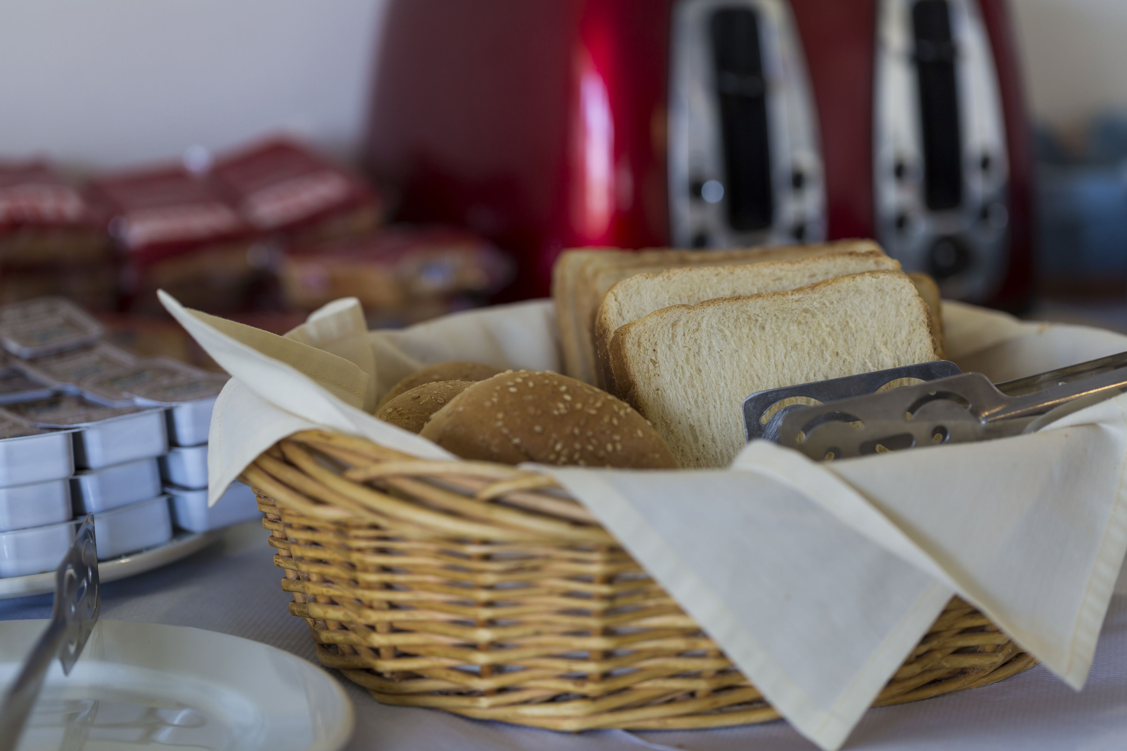 A wicker basket containing sliced bread and a knife on a table.