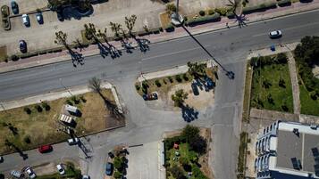 Vue aérienne d’une zone urbaine côtière, avec des parkings, des routes et des espaces verts.