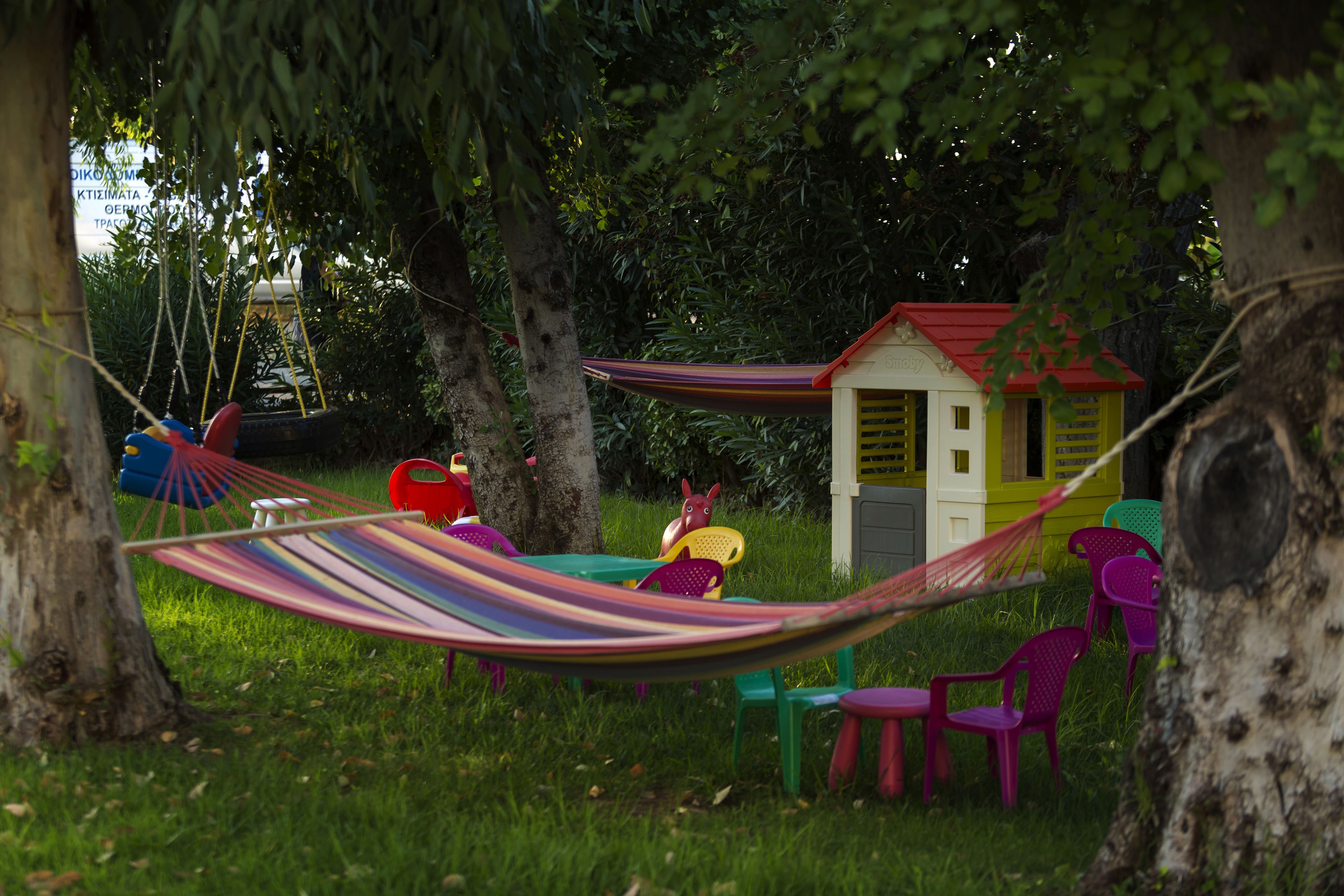 Eine Hängematte, ein kleines Haus und Plastikstühle auf einer Wiese.