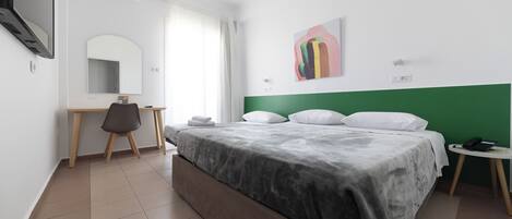 Une chambre d’hôtel avec un lit, un bureau, une chaise, une télévision et un tableau au mur.