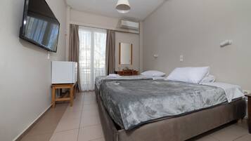 Camera d'albergo con un letto, una televisione a parete, un tavolino e una finestra con tende.