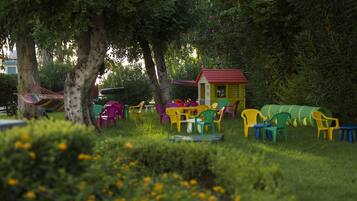 A garden with colorful plastic chairs and a small yellow building.