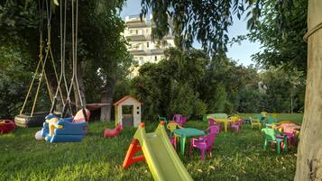 Un parque infantil con toboganes, columpios y sillas y mesas de plástico de colores.