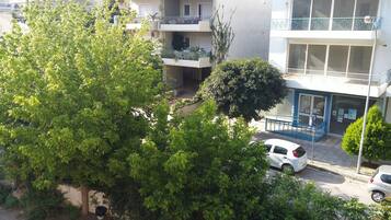 Un edificio residencial de varios pisos con balcones, una entrada protegida por un portón y un árbol en primer plano.