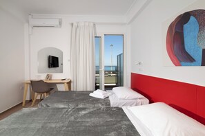 Habitación de hotel con cama, escritorio, silla, televisión y un amplio ventanal con vistas.