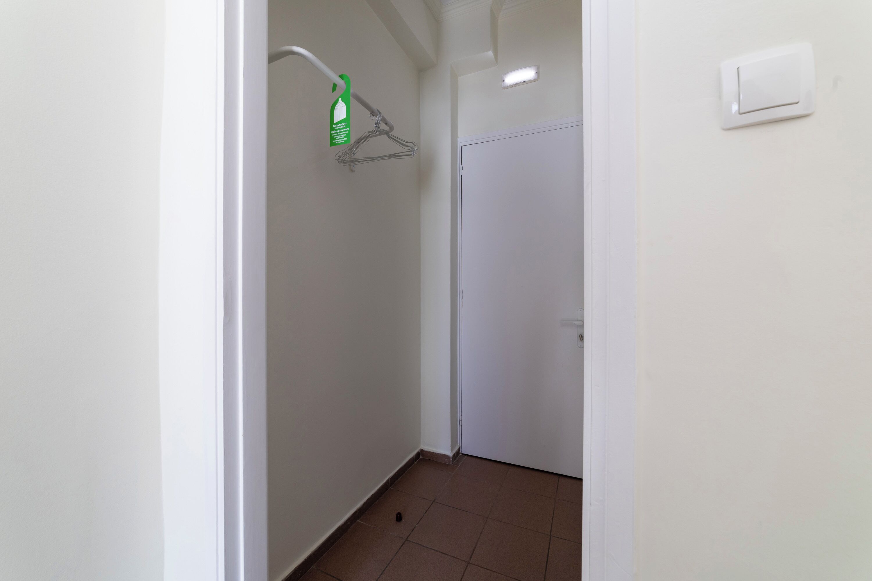 A narrow hallway with a shower area, a door, and a light switch on the wall.