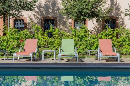 Una piscina al aire libre, sillones reclinables de piscina