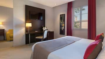 Une chambre d’hôtel avec un grand lit, un bureau avec une chaise, une télévision et une fenêtre avec des rideaux rouges.