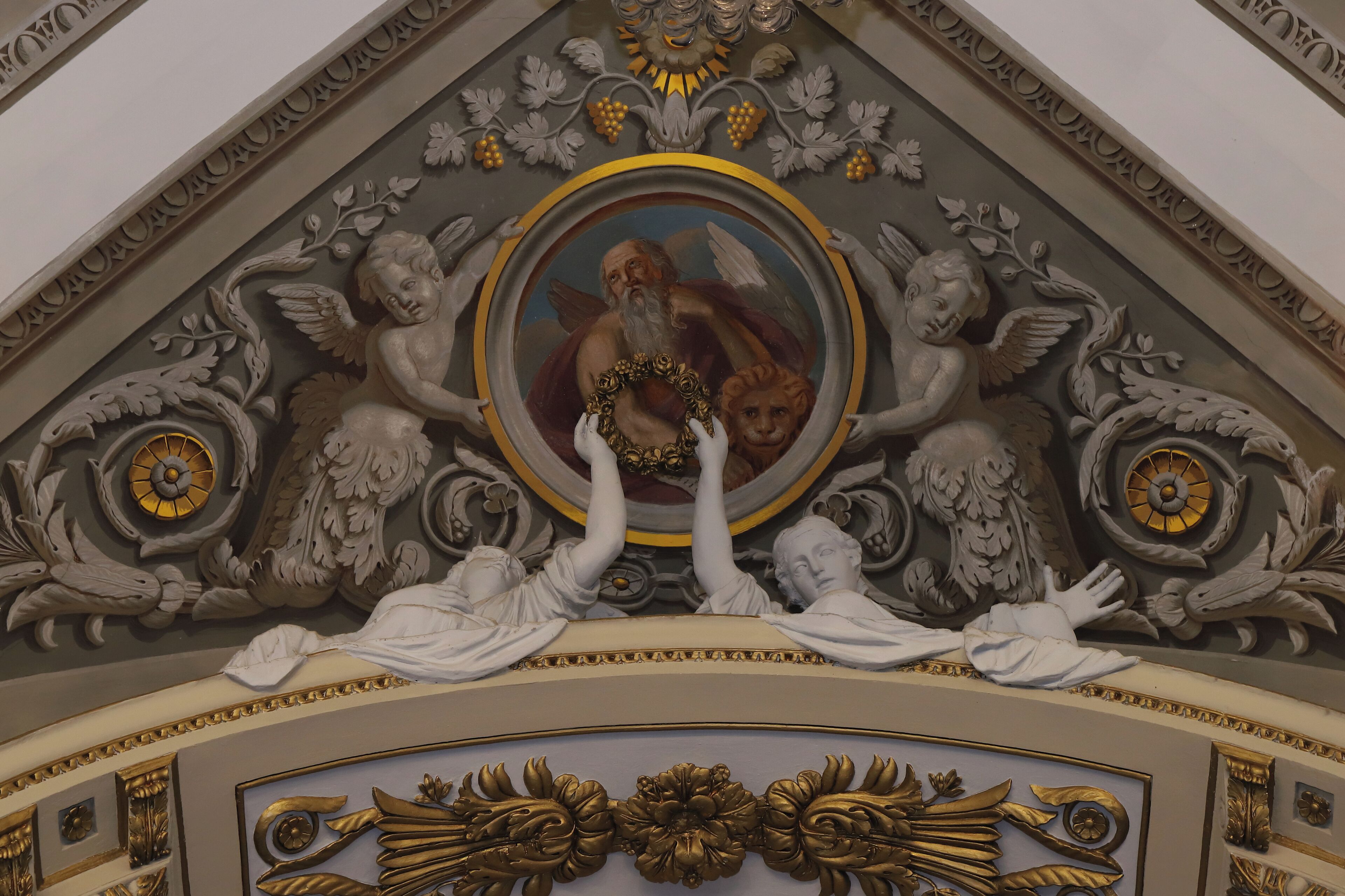 A detailed ceiling with ornate carvings and a central circular artwork.