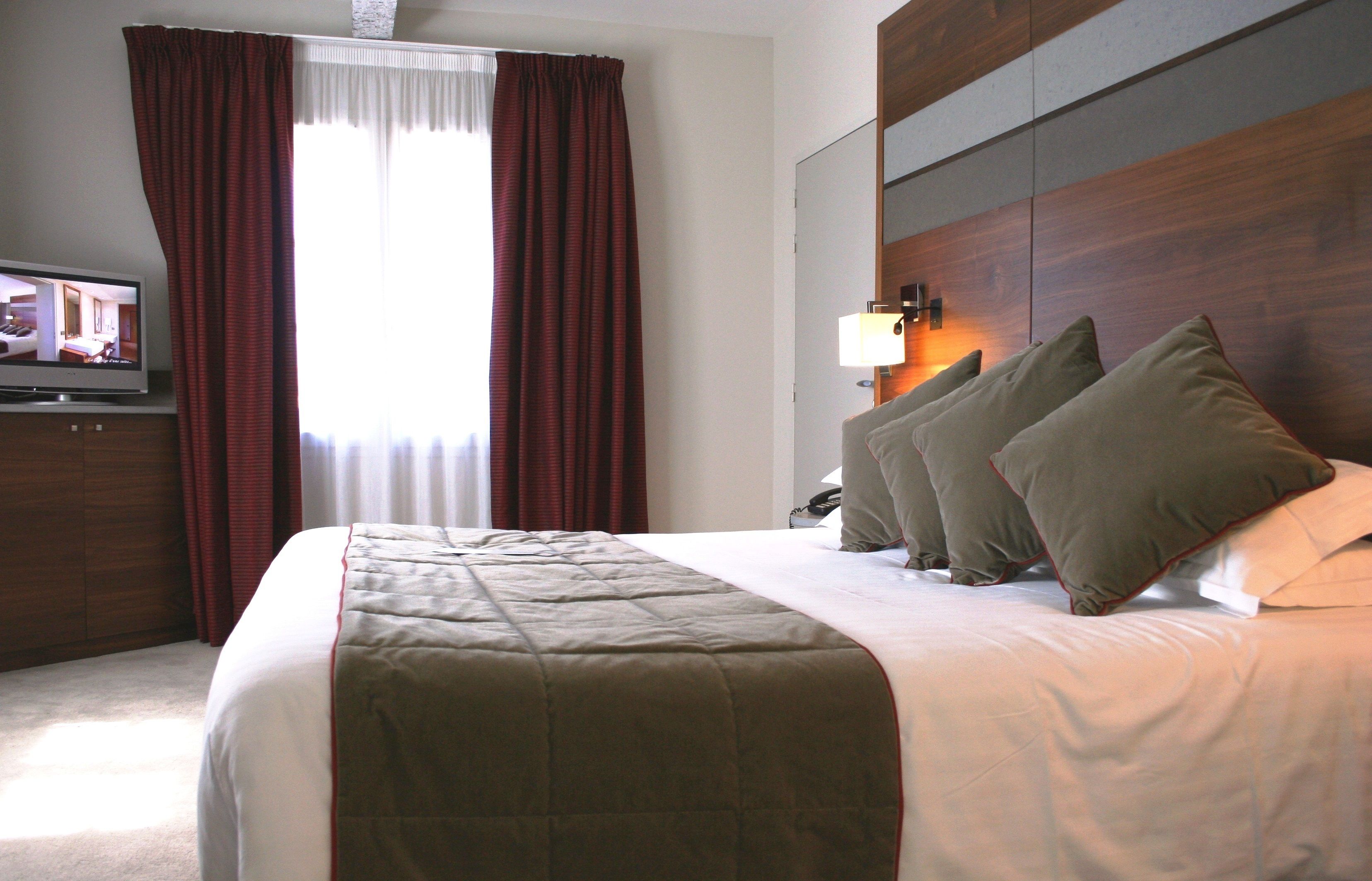 Ein Hotelzimmer mit einem großen Bett, einem Fernseher auf einem Schrank und einem Holzkopfende.
