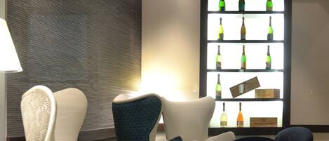 Un área de lounge moderna con una pared estampada, una exhibición de botellas y asientos contemporáneos.