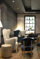 Un área de lounge moderna con una pared estampada, una exhibición de botellas y asientos contemporáneos.