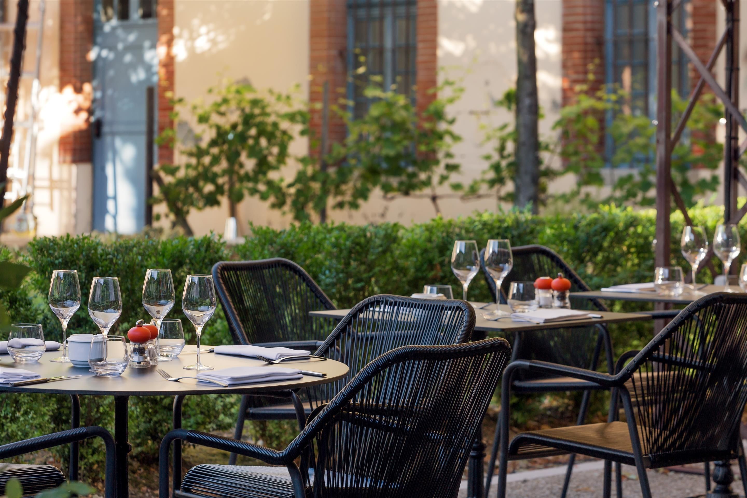 Mesas de comedor al aire libre con sillas, copas de vino y un menú.