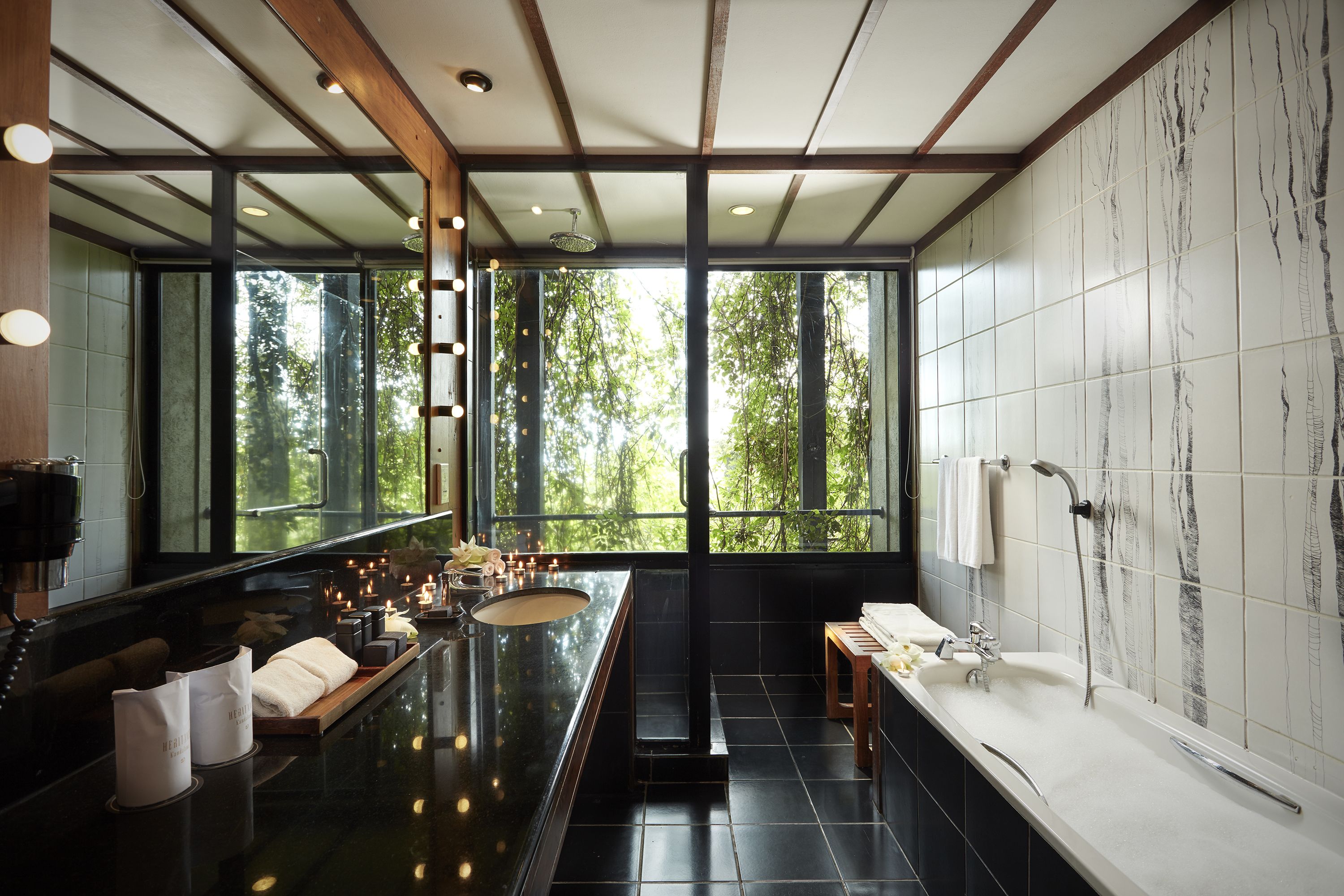 A modern bathroom with a large mirror, a bathtub, and a sink.