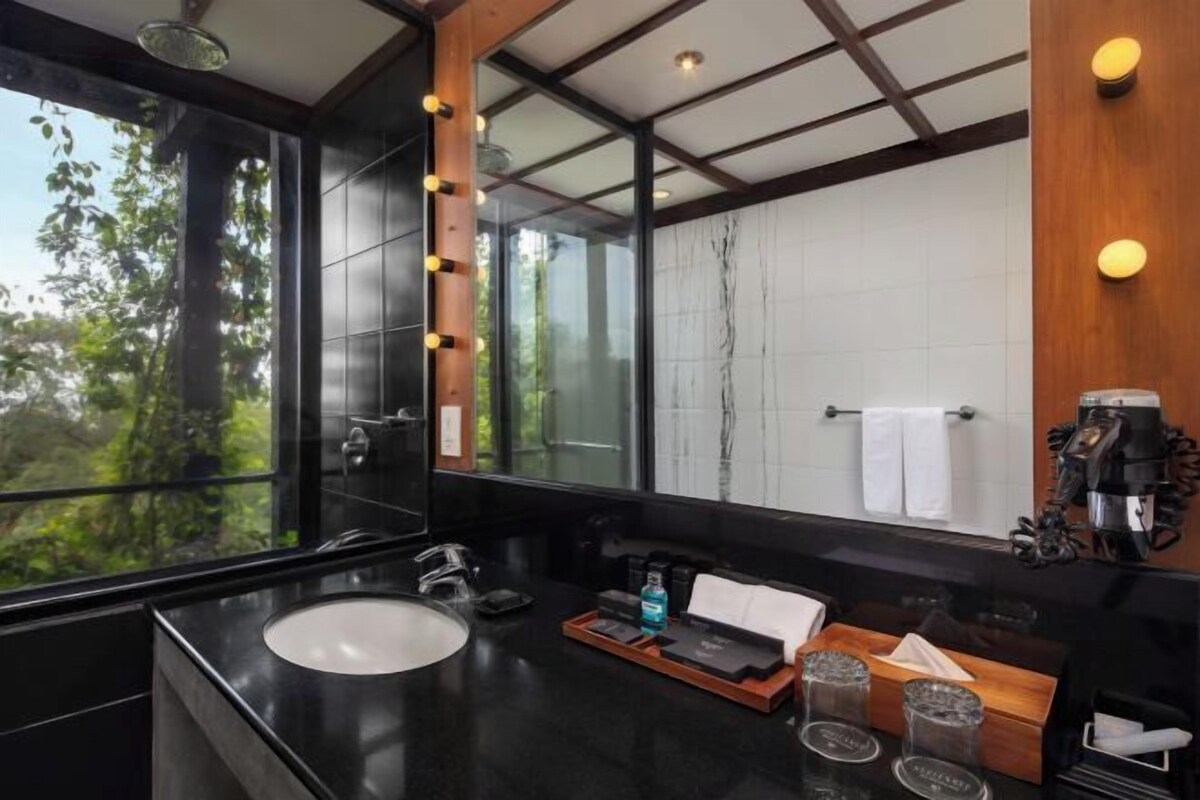 Un baño moderno con un ventanal grande, un lavamanos y una cafetera.
