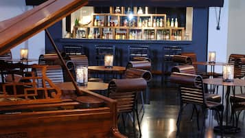 A piano bar with a bar counter, shelves of liquor bottles, and several tables with chairs.
