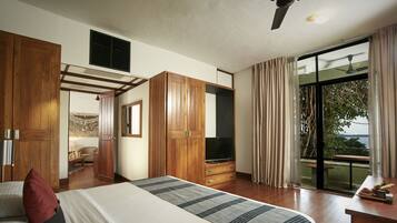 A bedroom with a large bed, wooden wardrobe, a TV, and a balcony with a view.