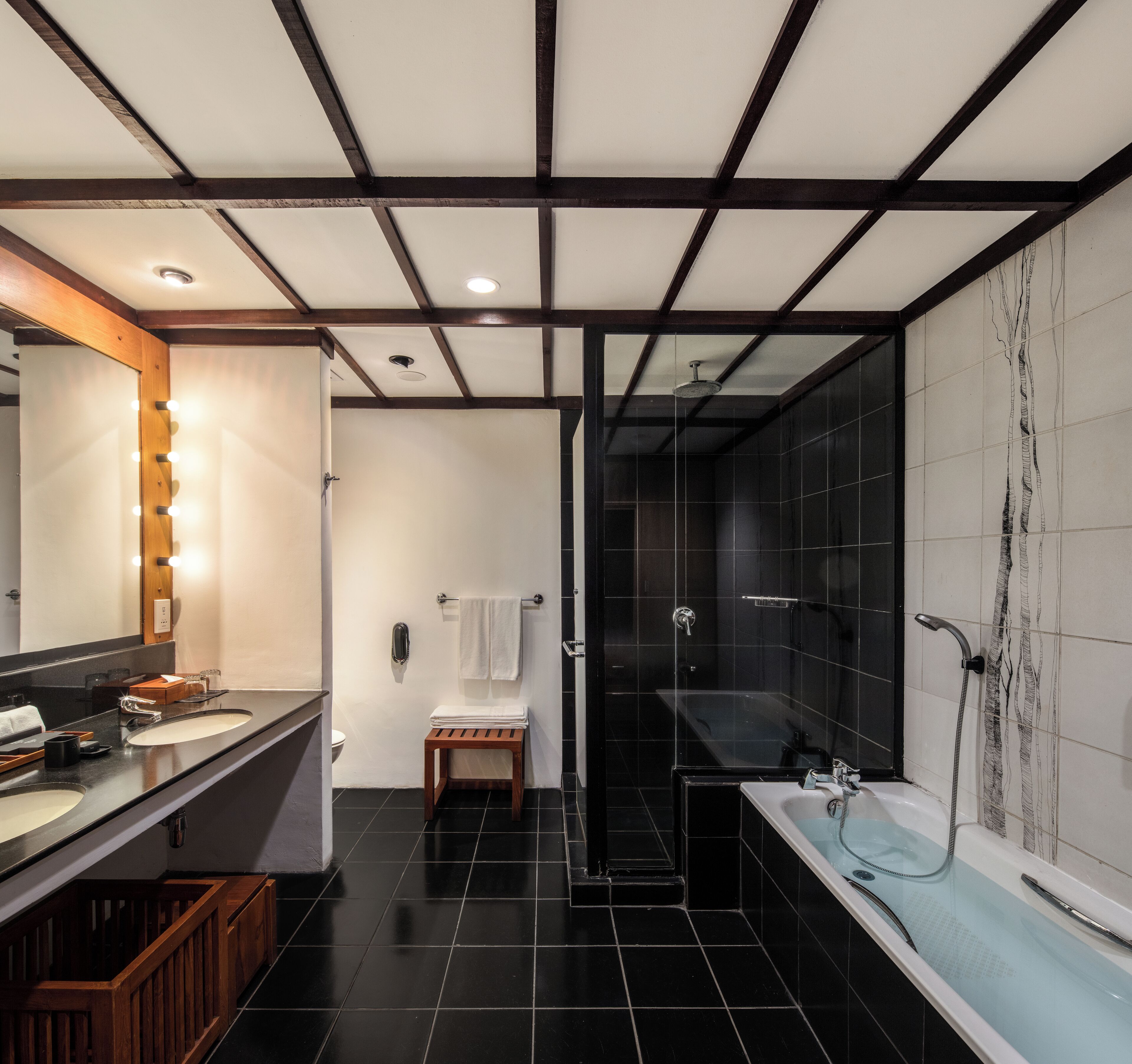 A modern bathroom with a large mirror, two sinks, a shower, and a bathtub.