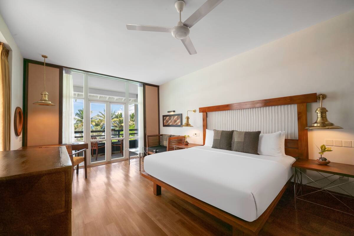 A spacious bedroom with a large bed, a desk, and a ceiling fan.