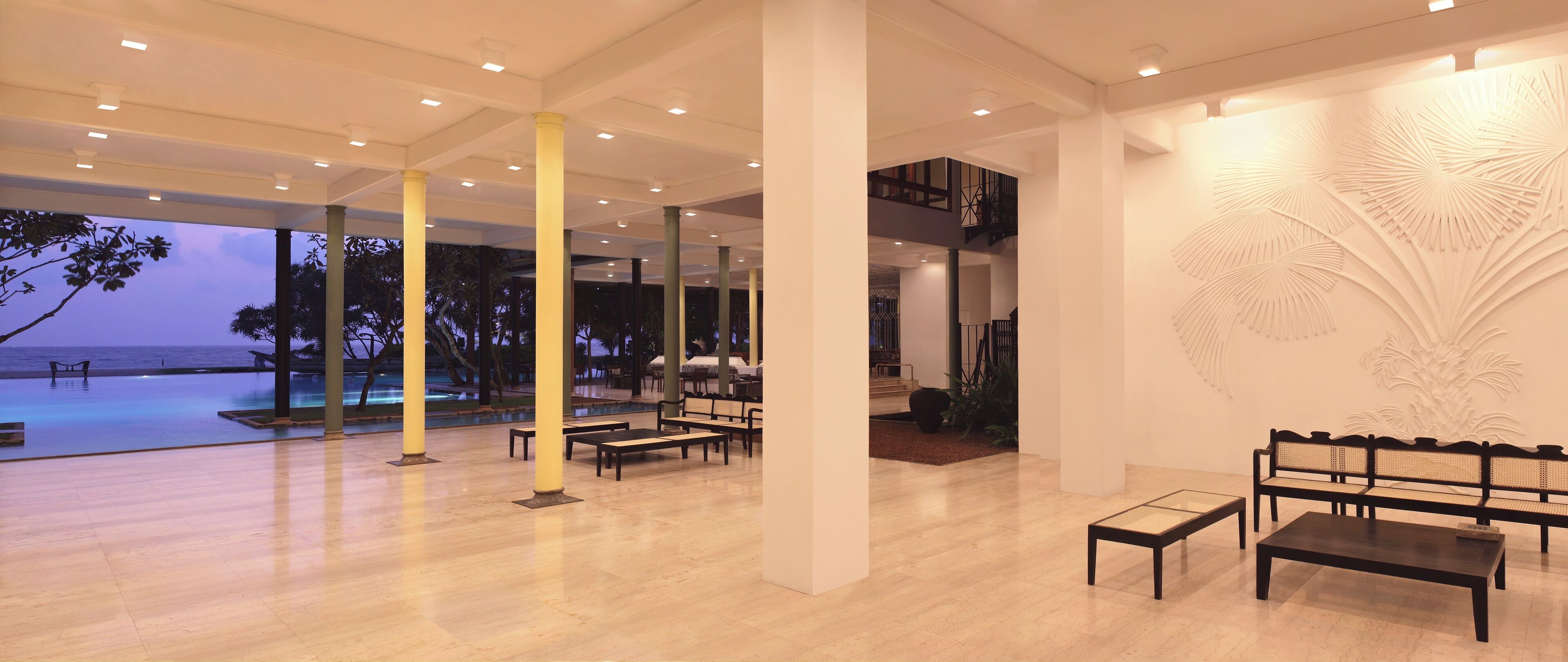 A spacious lobby with a pool view, modern furniture, and a decorative wall.