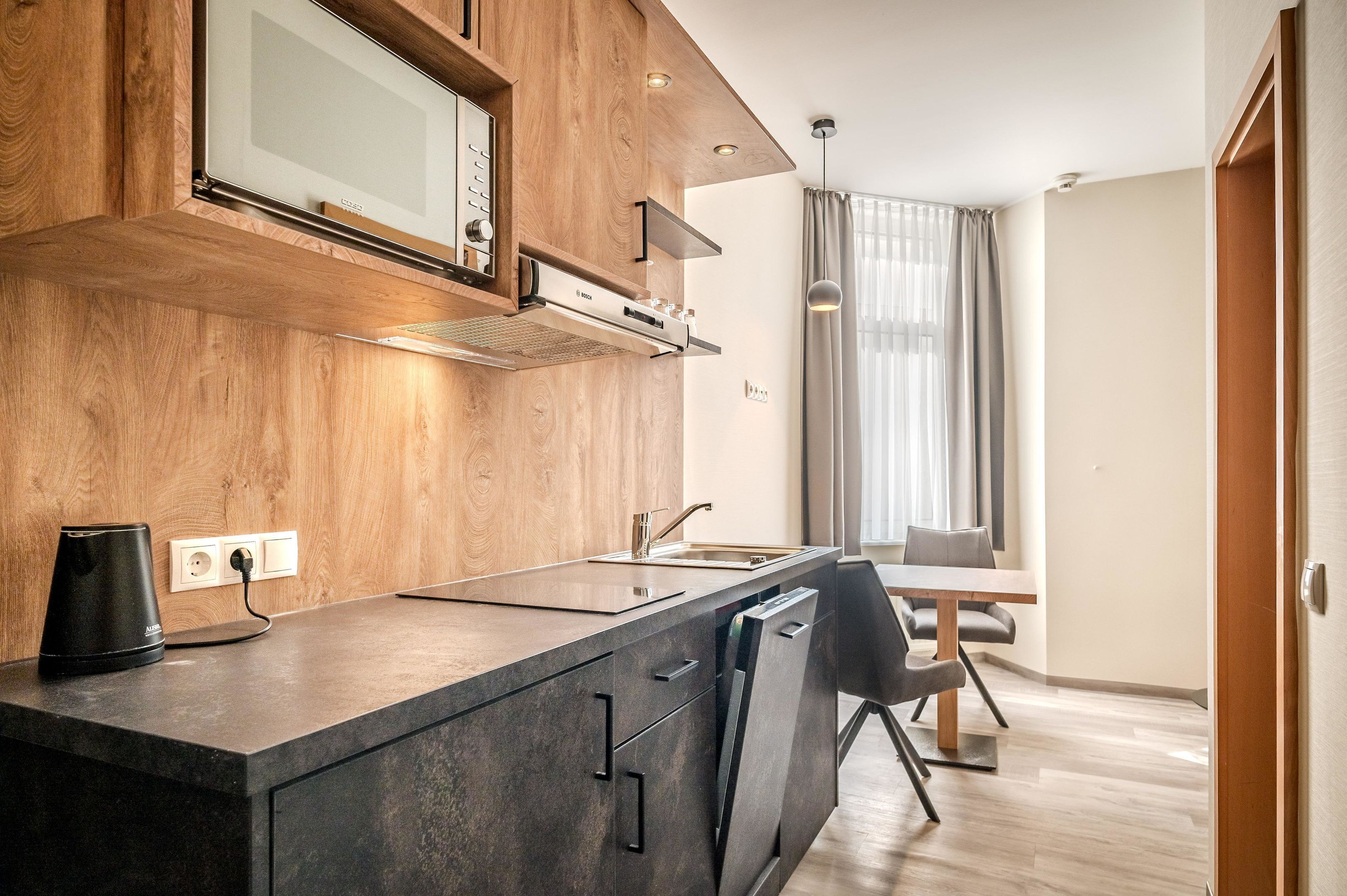 A modern kitchen with wooden cabinets, a built-in microwave, and a coffee maker.